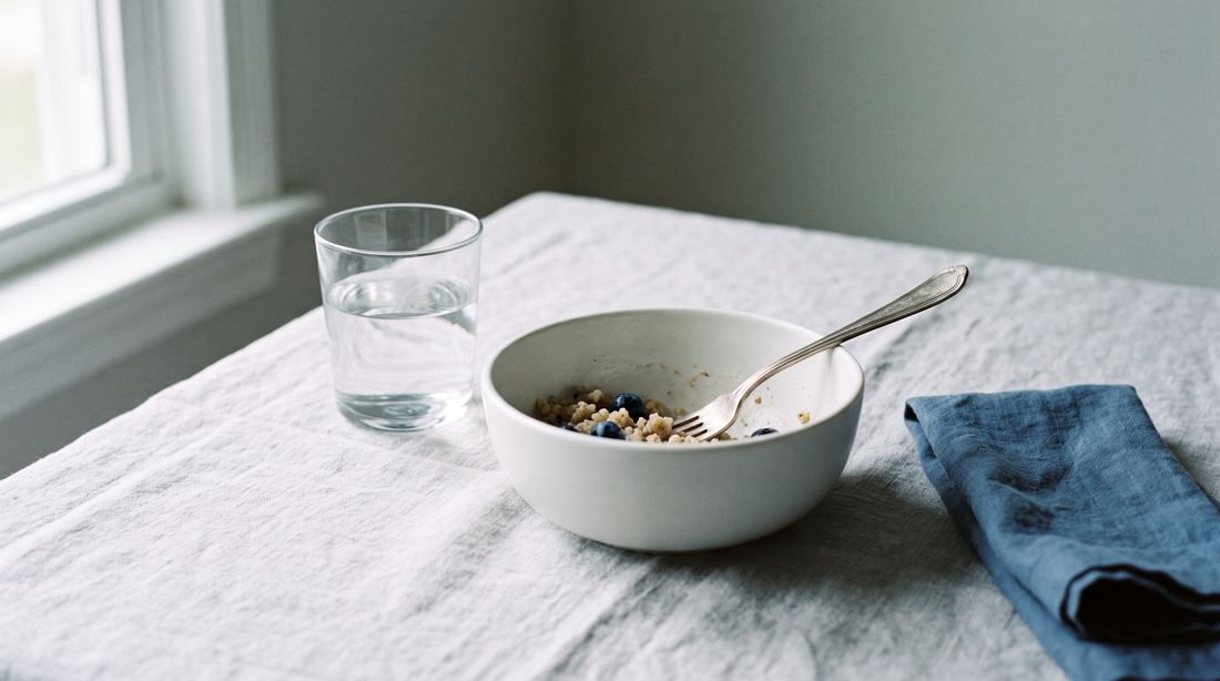 A simple place setting with a plain white bowl, a fork and a glass of water