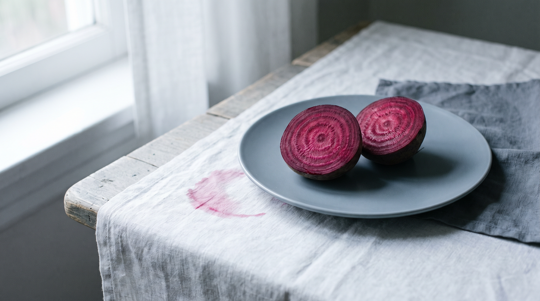 Two halves of a raw beetroot cut side up on a pale ceramic plate