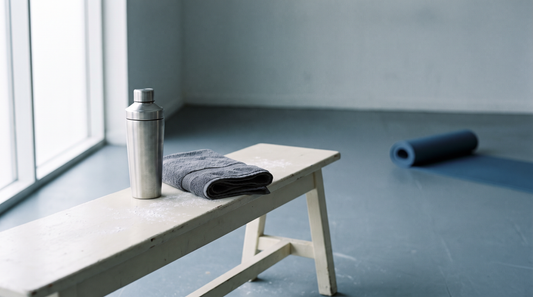 An empty gym bench in quiet side light with a steel shaker bottle and a folded towel